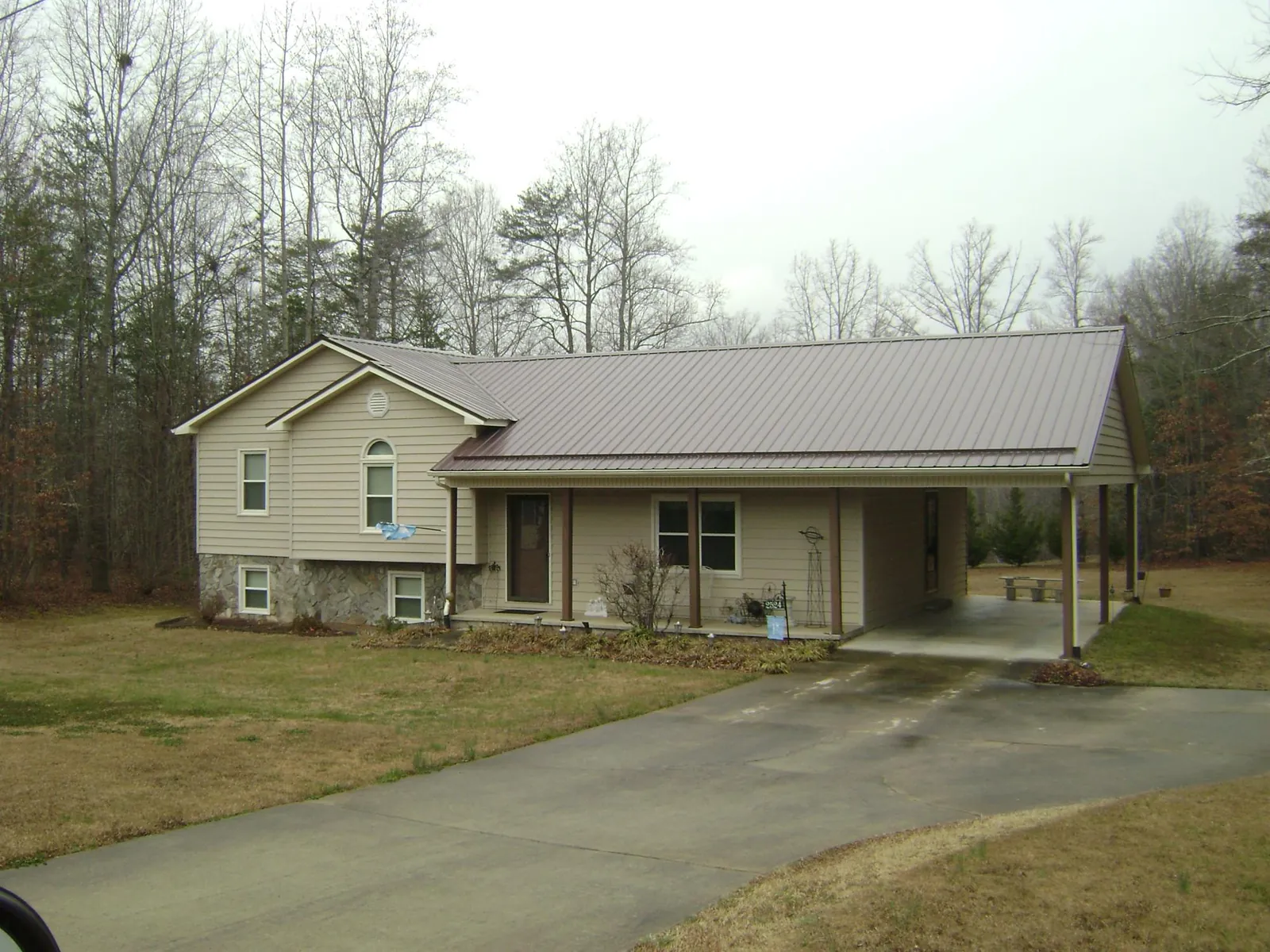 Brown metal roof on a tan split level home with an attached carport in Lorton
