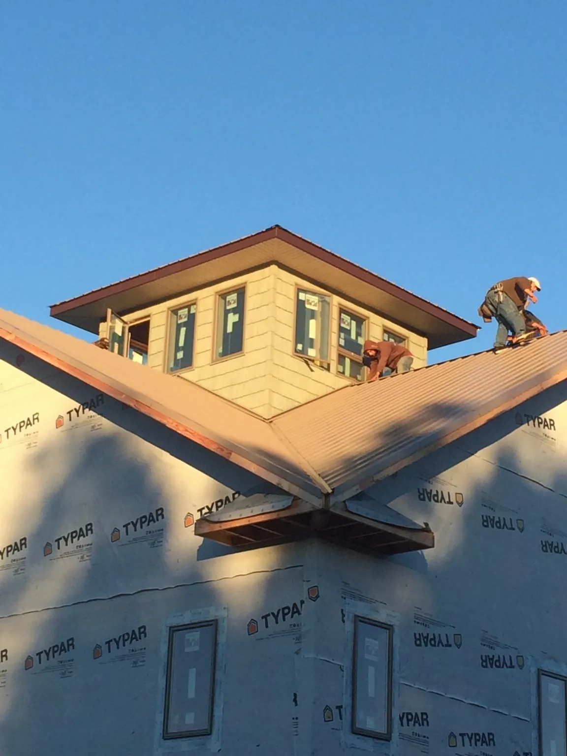 Roofers working around a rooftop cupola on a new metal roof at sunset — Roof Waterproofing in Lorton by Roofing Brothers